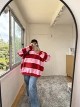 Buzo oversize a rayas horizontales rosas y rojas con cuello redondo y logo bordado en el pecho.