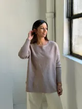 Sweater de punto en color visón, con cuello redondo, manga larga y diseño holgado con aberturas laterales en el ruedo.