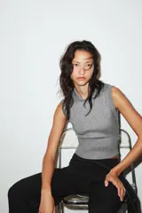 Chaleco de punto color blanco, estilo polo, sin mangas (manga sisa) y cuello solapa. La parte inferior termina en rib.