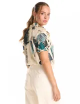 Blusa de gasa con estampado abstracto en tonos beige, azul y verde. Presenta cuello mao fruncido con lazos ajustables, escote en V y mangas cortas con volados y puños elásticos.