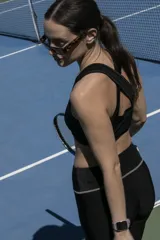 Top deportivo negro con breteles cruzados en la espalda y detalle de medialuna en la parte inferior delantera.