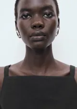 Top negro sin mangas de cuello cuadrado y tirantes anchos, con diseño recto y cierre de cremallera lateral.