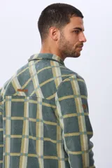Sobrecamisa leñadora de polar a cuadros en tonos verde militar, beige y azul claro. Cuenta con dos bolsillos frontales con solapa, dos bolsillos laterales y cierre con botones a presión. Interior de micropolar.