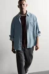 Camisa regular fit de denim de algodón con efecto lavado, cuello solapa y manga larga con puño abotonado. Tiene un bolsillo de parche en el pecho con detalle bordado a contraste y cierre frontal con botonadura.