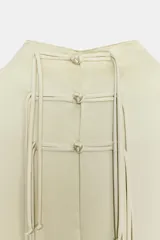 Vestido midi de Zara Woman Collection confeccionado en hilatura de viscosa con tejido satinado, de color beige. Presenta cuello subido, diseño sin mangas (manga sisa), bajo recto con aberturas laterales y cierre en la espalda con alamares.