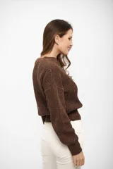 Sweater de punto con cuello redondo, diseño de trenzas frontales y acabado con hilo metálico brillante. Presenta puños y cintura ajustados en tejido acanalado.