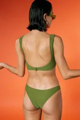 Top de bikini verde militar con textura arrugada, escote amplio y breteles fijos. Incluye bombacha vedetina con frente en V.