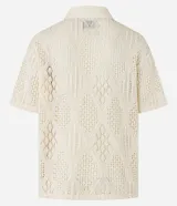 Camisa polo de mangas cortas color crema, confeccionada en tejido de punto calado con cuello inglés.