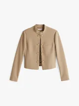 Americana beige de corte slim con cuello mao, cierre de gancho oculto, bolsillo de ojal en el pecho, totalmente forrada y logo esmaltado de Tommy Hilfiger en el puño.