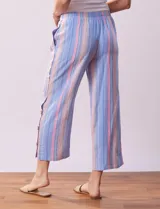 Pantalón de algodón estampado a rayas verticales azules y blancas, marca Erika. Tiene pretina elastizada, bolsillos delanteros, ruedo lateral con tajo y botones decorativos.