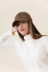Gorra de diseño clásico con visera curva, confeccionada en material símil gamuza color bordó. Presenta un logo metálico con la palabra Peach en la parte frontal y cuenta con un sistema de ajuste posterior.