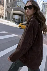 Cazadora de ante color marrón oscuro, con cuello solapa, manga larga y cierre frontal de botones. Incluye dos bolsillos delanteros de plastrón con solapa.