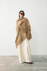 Ruana tejida en lana merino extrafina con lino y viscosa, de diseño triangular con textura en relieve y flecos en los bordes. Pieza versátil de calce holgado y envolvente.