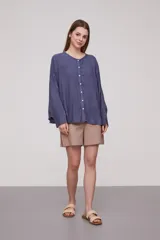 Camisa de corte holgado y diseño amplio, con cuello redondo y cierre frontal de botones. Presenta mangas largas con caída fluida y puños sencillos.