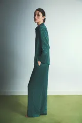 Pijama de dos piezas compuesto por camisa de manga larga con cuello camisero y botones frontales, y pantalón de corte recto y holgado con cintura elástica y cordón de ajuste. Presenta un diseño estampado con pequeños corazones en tono sobre tono.