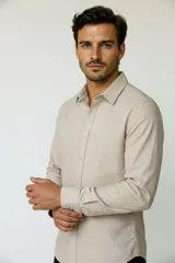 Camisa de poliéster color marrón, de corte holgado, con mangas largas, cuello camisero clásico y cierre frontal de botones.