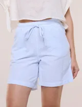 Short de algodón color celeste con sutiles rayas blancas, de silueta holgada, pierna recta y pretina fruncida con elástico y cordón de ajuste.