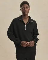 Buzo deportivo negro de corte oversize, confeccionado en tejido DoubleSoft®. Presenta cuello con paneles, media cremallera metálica y puños y bajo amplios.