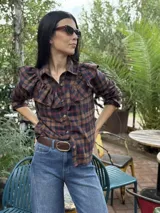 Camisa blanca de algodón con cuello clásico, cierre frontal de botones y detalle de volados en la parte delantera que se extienden hacia los hombros.