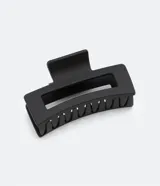 Pinza para el pelo rectangular de plástico color negro con diseño vazado.