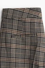 Pantalón de vestir con estampado a cuadros Príncipe de Gales en tonos marrón, negro y beige. Presenta un corte recto de pierna ancha, talle alto con pretina prolongada y cierre oculto.