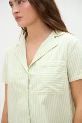 Vestido camisero de algodón con diseño a rayas verticales en tono amarillo claro, cuello solapa y cierre frontal de botones.