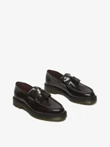 Mocasín Dr. Martens modelo Adrian, color bordó brillante, con borlas y costuras visibles. Confeccionado en cuero Arcadia, con empalmillado Goodyear y suela con cámara de aire resistente.