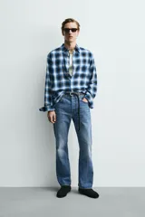 Camisa de corte regular fit confeccionada en tejido fluido de algodón y viscosa. Presenta un diseño de cuadros, cuello solapa, manga larga con puños abotonados, bolsillo en el pecho y cierre frontal con botones.