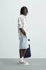 Bermuda de denim de algodón, color verde claro lavado, de corte recto y tiro medio. Presenta cinco bolsillos y cierre frontal con cremallera y botón.