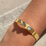 Brazalete rígido dorado con tres piedras ovaladas de labradorita.