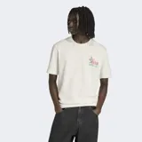 Remera blanca de algodón con cuello redondo y corte clásico. Presenta un pequeño estampado en el pecho que incluye la mascota Pique del Mundial México 86 y el logo de Adidas.