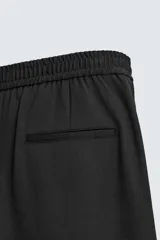 Pantalón regular fit color marrón oscuro, confeccionado en tejido con viscosa. Cuenta con cintura elástica, bolsillos delanteros y detalle de bolsillos traseros de vivo. El cierre frontal es con cremallera y botón.