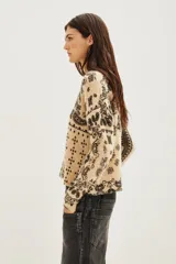 Sweater de punto con diseño estampado estilo paisley en tonos beige y negro, de cuello redondo y manga larga.