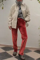 Pantalón de terciopelo color naranja, de corte recto y tiro medio con cierre frontal de botón y bolsillos.