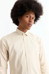 Camisa de manga larga color crema, con cuello camisero y botones frontales. Corte ajustado.