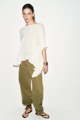 Top de cuello redondo color celeste con textura fruncida, mangas tipo capa y bajo asimétrico.
