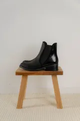 Botinetas de cuero color marrón con diseño tipo chelsea, con paneles laterales elásticos y detalle de cuero texturizado con acabado metalizado en el talón. Poseen taco bajo cuadrado y terminación redondeada.