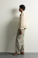 Cazadora cropped fit de algodón color beige, con cuello solapa, manga larga y cierre frontal de cremallera. Cuenta con bolsillos de vivo en la cadera, acabados elásticos y detalle de bordado a tono en el pecho.