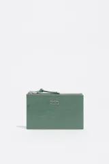 Monedero rectangular de Bimba y Lola, color verde esmeralda, con acabado brillante texturizado que simula piel de cocodrilo. Posee un cierre superior con cremallera y tirador de tela anudado. El logo metálico de la marca se encuentra centrado en la parte frontal.