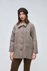 Chaquetón de lana fina con diseño de corte recto, cuello camisero y cierre frontal de botones. Presenta bolsillos delanteros amplios y mangas con costura horizontal a media altura.