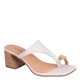 Sandalias de cuero color blanco marfil, con diseño de dedo estilo thong y detalle de aplique metálico dorado. Poseen taco ancho efecto madera y punta cuadrada.