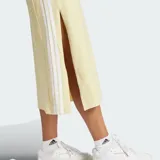 Vestido midi de corte recto sin mangas, color amarillo claro, con cuello redondo y las clásicas tres tiras blancas de Adidas a lo largo de los laterales.