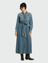 Vestido camisero largo de denim azul claro, con cuello camisero, botones frontales, bolsillos de parche en el pecho y mangas largas. Incluye un cinturón ancho de la misma tela anudado a la cintura.