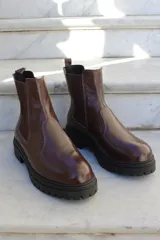Bota tipo chelsea de cuero color chocolate, con paneles laterales elásticos y suela track de goma negra.