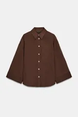 Camisa de corte oversize color marrón, con cuello solapa, mangas anchas por debajo del codo y bolsillo delantero de plastrón. Cierre frontal con botones.