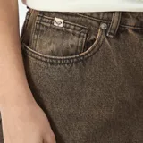 Bermuda de denim de tiro alto, color marrón con efecto desgastado, bolsillos delanteros y traseros, y cierre de botón y cremallera.