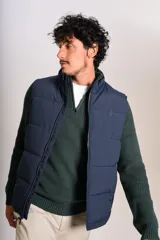 Chaleco tipo puffer color azul marino, con cierre frontal completo, cuello alto y logo bordado en el pecho.