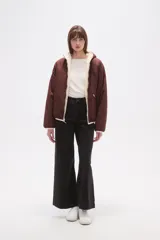 Campera de abrigo de tejido polar (tipo sherpa) color gris oscuro, con capucha y cierre frontal. Presenta paneles de color negro en los hombros y mangas, ribeteados con un vivo de color claro.