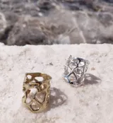 Anillo ancho de diseño orgánico y calado, con apariencia de red o magma solidificado.