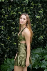 Vestido corto negro con estampado de plumas doradas, escote en V, breteles finos cruzados en la espalda, cut-outs laterales y volado en el ruedo.